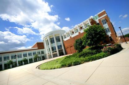 Angle view of a large modern brick and glass engineering building under a blue, cloudy sky.