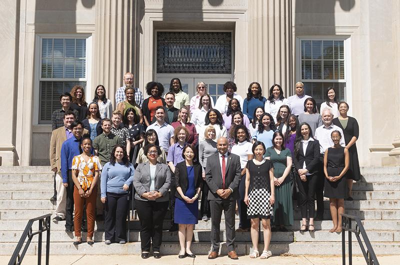 A large group of Counseling Center staff members in professional attire stand on the Shoemaker Building steps.