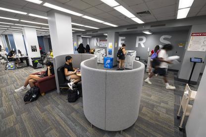 Students study in curved privacy pods in McKeldin library with printers in the background.
